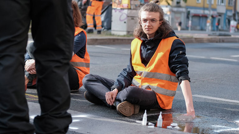 Ein Mann hat sich auf der Straße festgeklebt.