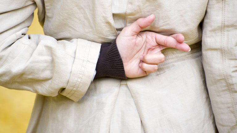 Eine Frau kreuzt ihre Finger hinter dem Rücken