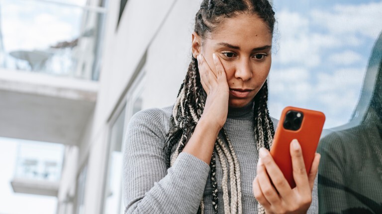 Frau schaut erschrocken aufs Handy