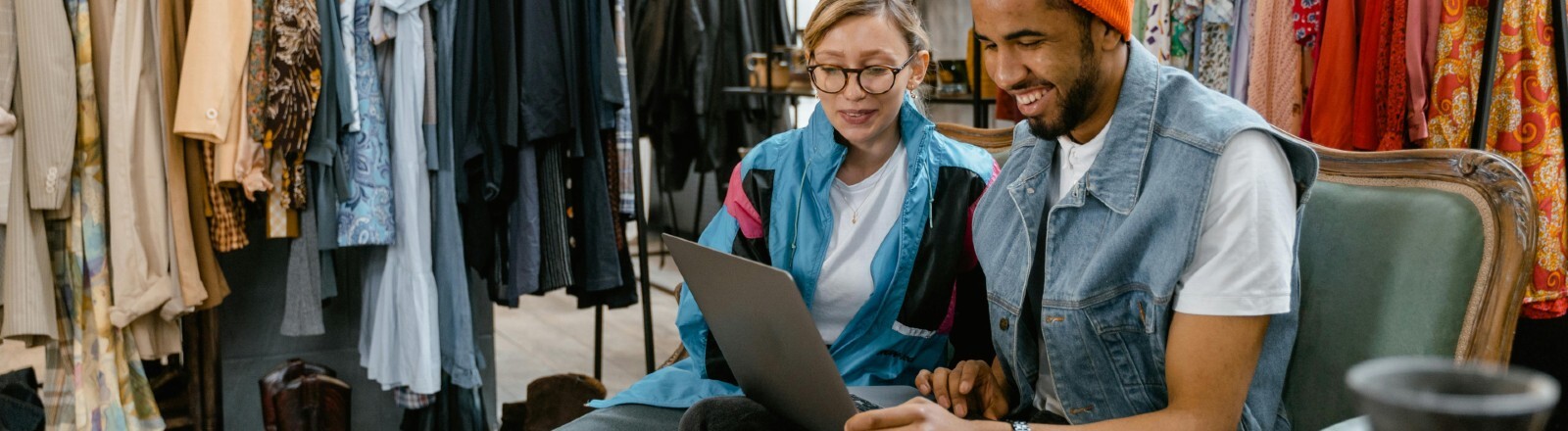 Frau und Mann sitzen in einem Klamottengeschäft und shoppen online