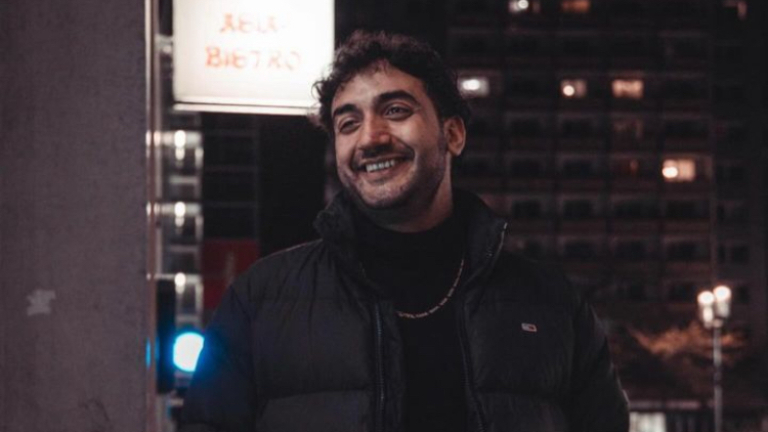 Robert lächelnd in schwarzer Jacke, schwarzem Oberteil und Silberkette