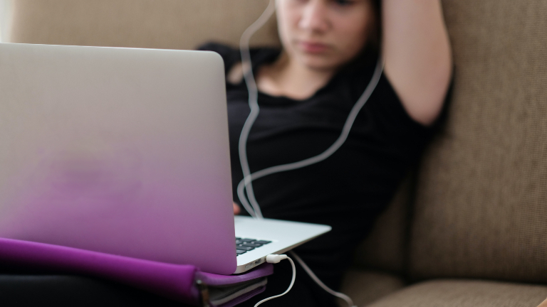 Frau sitzt müde aufm Sofa vor Laptop