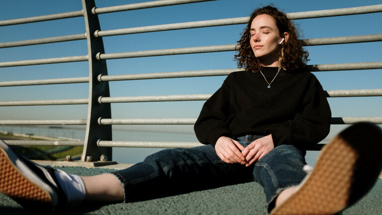 Das Foto zeigt eine Frau, die über Kopfhörer Musik hört