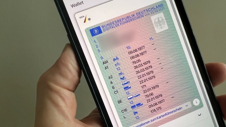 Ein Mann hält ein iPhone mit der App "ID Wallet", in der die digitale Variante eines Führerscheins zu sehen ist.