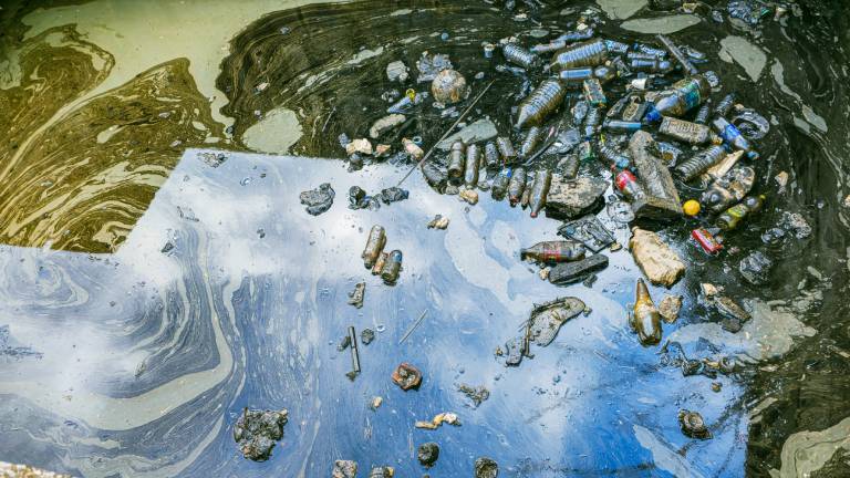 Starke Wasserverschmutzung in einem Stadthafen in Izmir, Konak, Türkei, sichtbar: Treibende Plastikflaschen, Müll und ein giftiger Ölteppich treiben auf der Wasseroberfläche.