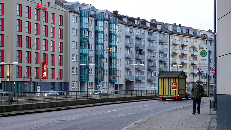 Wohnen in München: Eine Ansicht mit Wohnungen, einer Straße, Bürgersteig und einer Bushaltestelle