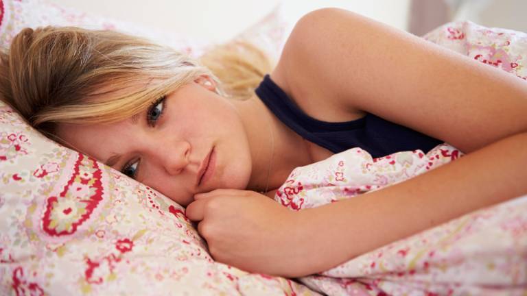 Frau liegt auf der Seite wach im Bett und schaut besorgt