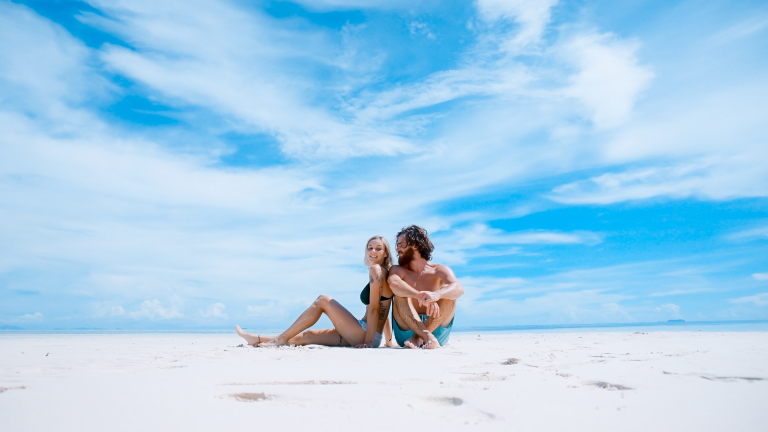 Ein junges Paar sitzt am Strand