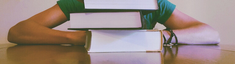 Person hinter einem Bücherstapel