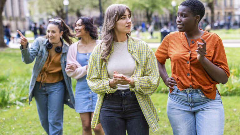Eine Gruppe junger Frauen spaziert gemeinsam durch einen Park.