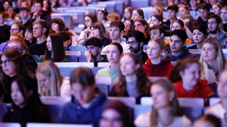 In einem großen Hörsaal sind die meisten Plätze von Studierenden belegt. Dort findet die Erstsemsterbegrüßung statt.
