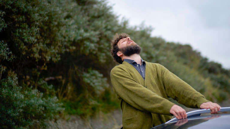 Ein Mann hält sich an einem Auto fest.