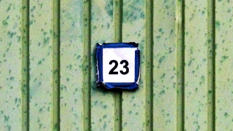 Auf einer grünen Wand hängt ein Schild, auf dem 23 steht.