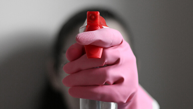 Frau mit Gummihandschuh und Sprühflasche