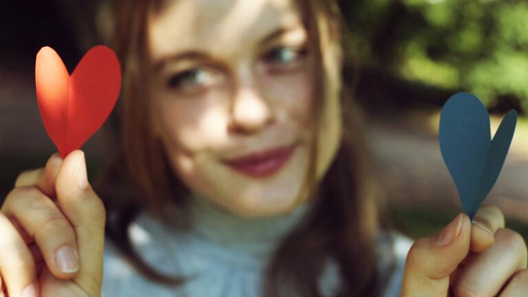 Eine Frau mit einem Herzen in jeder Hand.