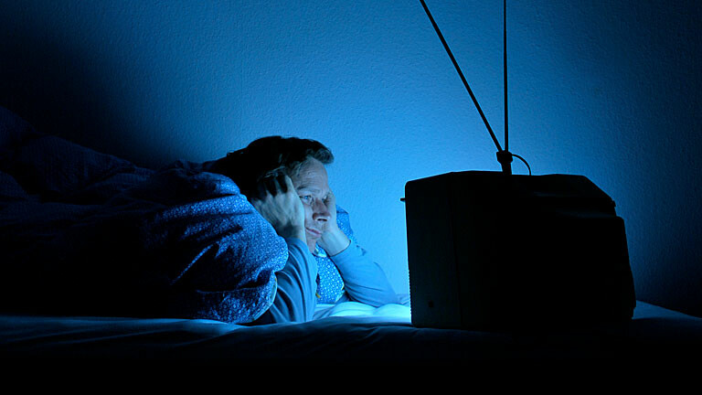 Mann schaut genervt Fernsehen