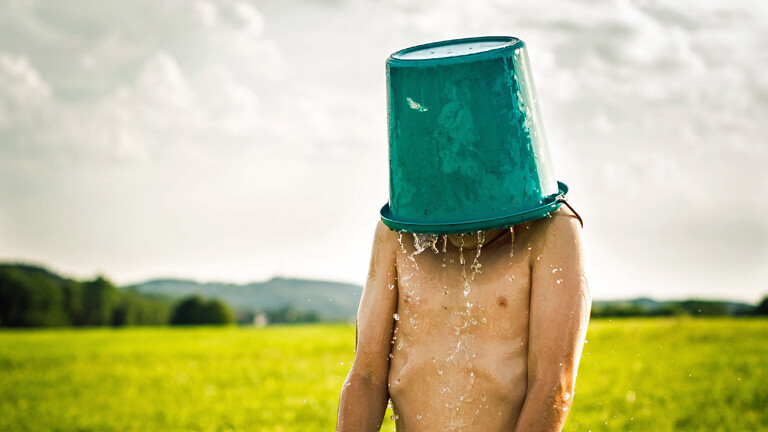 Ein Mann hat sich einen Eimer über den Kopf gestülpt.