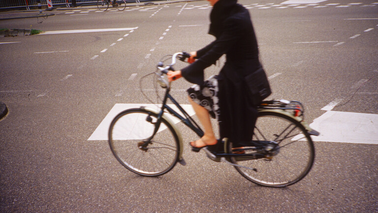 Eine Frau fährt auf der Straße Fahrrad.