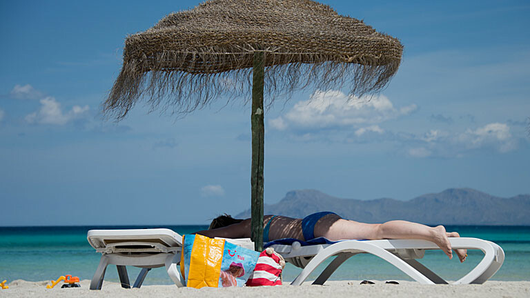 Eine deutsche Touristin liegt in Mallorca am Strand auf einer Liege, Bild: dpa