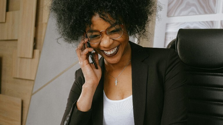 Eine Frau telefoniert und lacht dabei.
