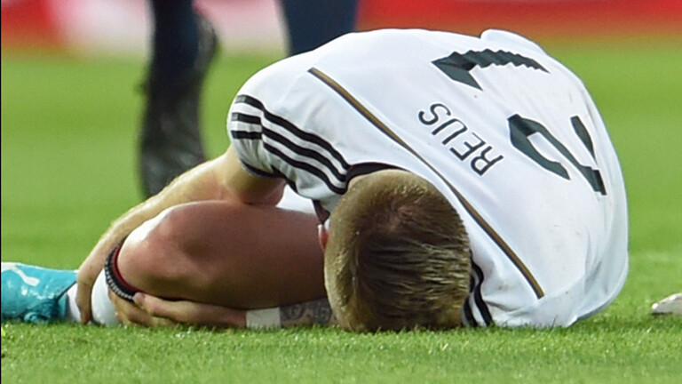 Der Fußballspieler Marco Reus liegt am Boden.