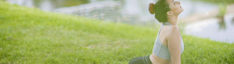 Frau bei einer Yogaübung auf der Wiese