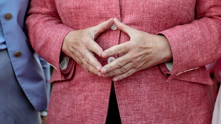 Angela Merkel hat ihre Hände zur Raute geformt.