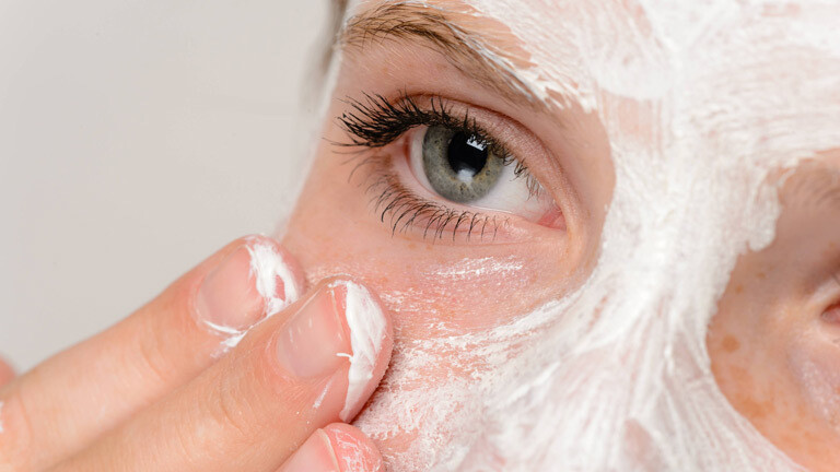 Eine Frau cremt sich das Gesicht ein.