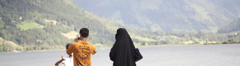 Eine verschleierte Touristin aus einem arabischen Land ist mit ihrer Familie am Seeufer in Zell am See im Bundesland Salzburg in Österreich zu Fuß unterwegs.