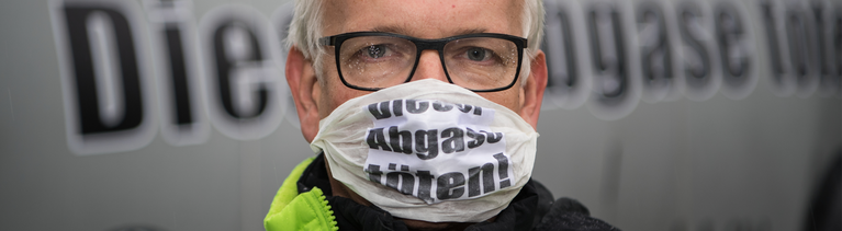 Der Bundesgeschäftsführer der Deutschen Umwelthilfe, Jürgen Resch, steht am 14.09.2017 mit einer Atemschutzmaske mit der Aufschrift "Diesel Abgase töten!" in Frankfurt am Main vor einer übergroßen PKW-Atrappe.