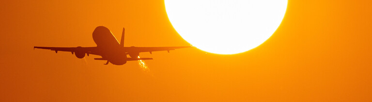 Ein Flugzeug startet bei Sonnenaufgang am Flughafen Düsseldorf.