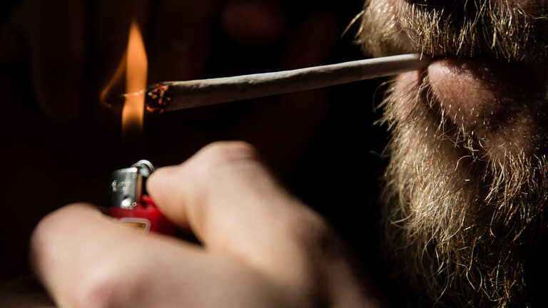 Schmuckbild zum Thema Kiffen. Ein Junger Mann baut und raucht einen Joint.