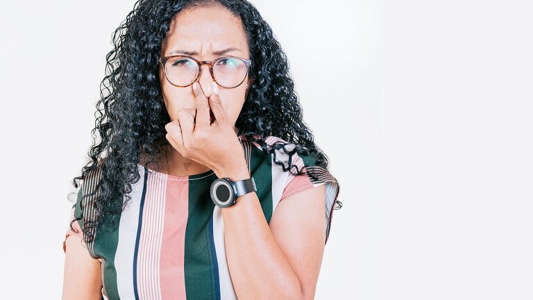 Angewiederte Frau hält sich die Nase zu