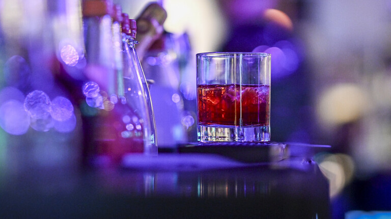 Ein einzelnes Glas mit einem Cocktail steht auf einem Tresen