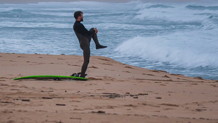 Ein Surfer dehnt sich am Strand