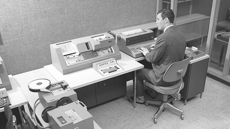 Schwarz-weiß Foto eines Mannes, der in den 1960er Jahren an einem Teil des Computers IBM System 360 arbeitet.