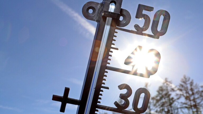 Symbolbild: Ein Thermometer vor blauem Himmel und der Sonne