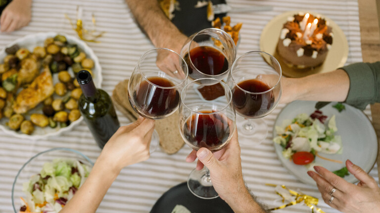 Hände von Menschen, sie stoßen mit Weingläsern an