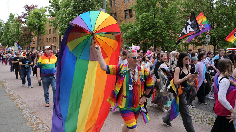 Menschen laufen mit Regenbogenfahne in der Pappelallee während einer Demo zum Christopher Street Day in Potsdam.