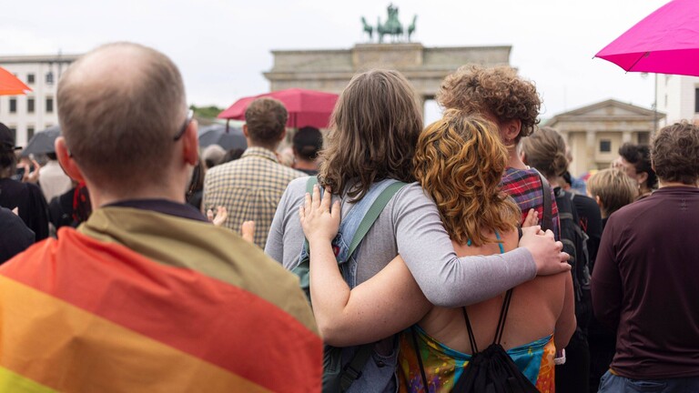 Trauernde Menschen umarmen sich vor dem Brandenburger Tor