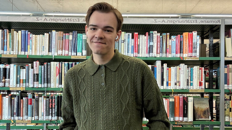 Jonny steht in einer Bibliothek