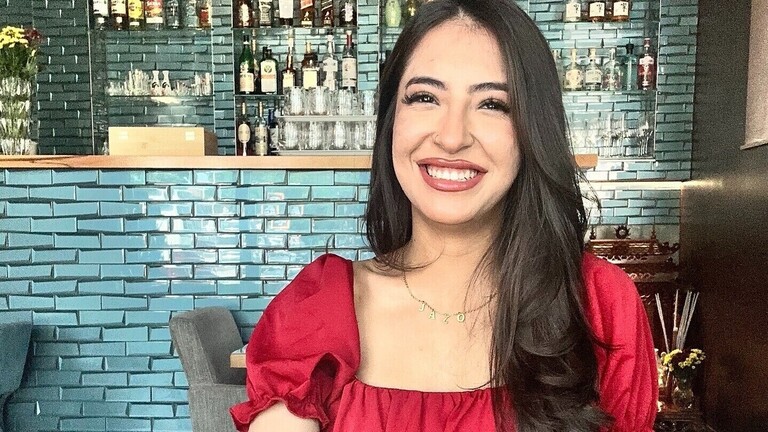 Jaylda - eine junge lachende Frau in einem roten Kleid.