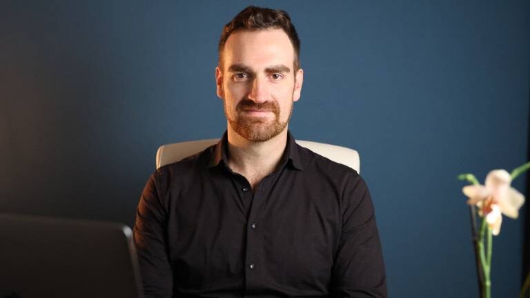 Ramón Schlemmbach in schwarzem Hend vor dunkelblauer Wand