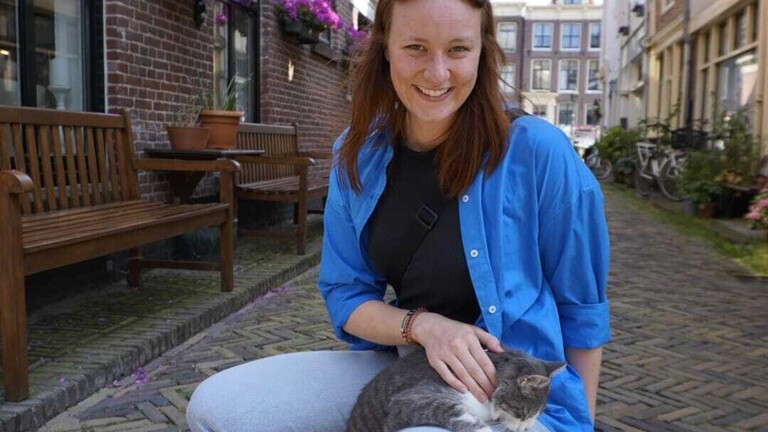 Kathi - eine junge Frau, die in der Kniebeuge am Boden hockt und ein kleines Kätzchen auf dem Schoß hat