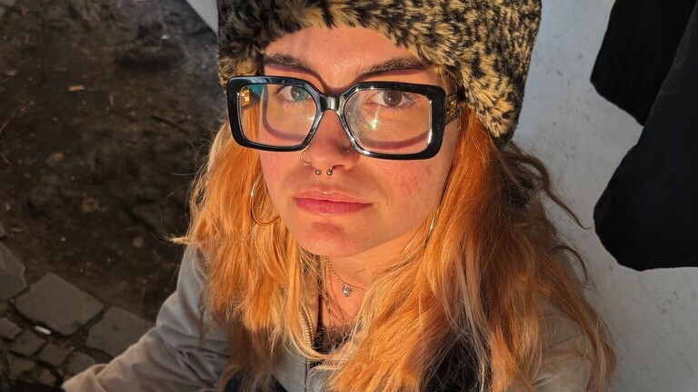 Eine junge Frau mit Brille blickt in die Kamera.