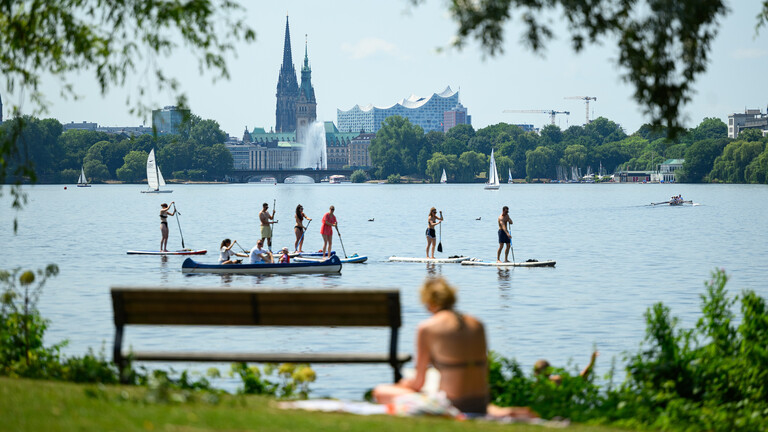 Menschen auf Stand-up-Paddles auf der Außenalster vor der Hamburger Skyline