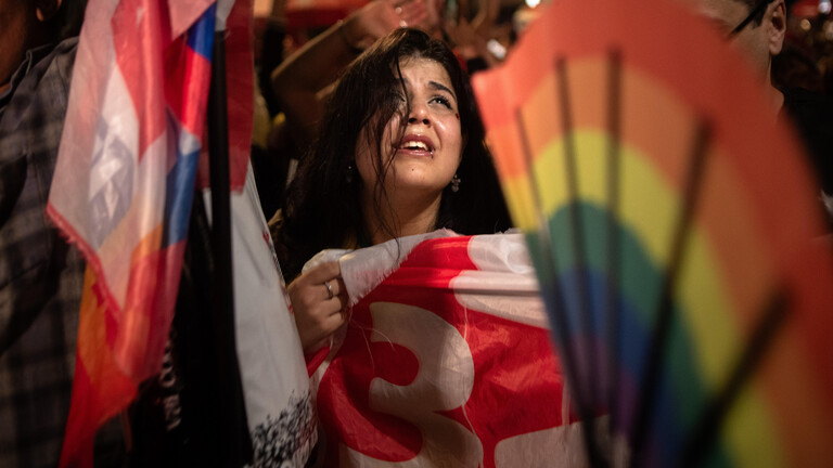 Eine Anhängerin des brasilianischen Präsidenten Luiz Inácio Lula da Silva, die eine Flagge der Arbeiterpartei (PT) in der Hand hält, kämpft mit den Tränen, als die Auszählung der Stimmen in der Stichwahl um das Präsidentenamt Lula dem Sieg näher bringt. (Avenida Paulista in São Paulo, Brasilien, am 25. Oktober 2026)