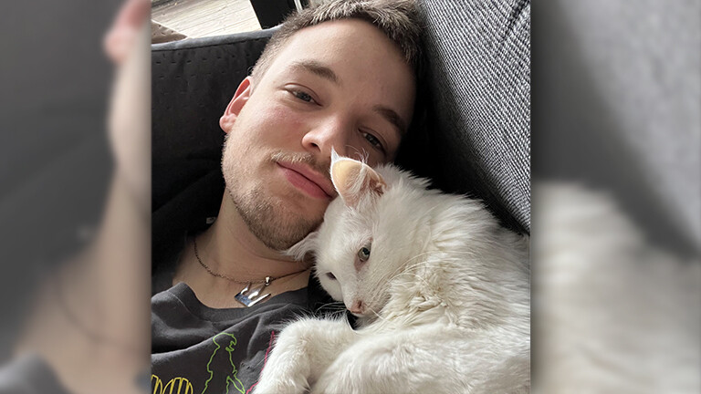 Daniel kuschelt mit seinem weißen Kater Balu