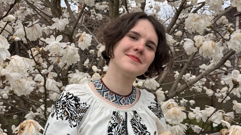 Sofia Oganesian stehr vor einem Baum mit weißen Blüten