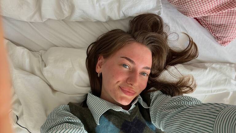 Michelle liegt auf ihrem Bett und macht ein Selfie.